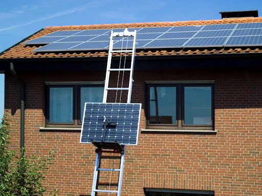 Solcellevogn på toplift stigeheis som frakter solcellepanel opp til tak med solcellepanel på