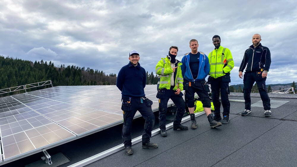 Fem ansatte i Thunestvedt AS på taket med ferdig monterte solcellepanel.